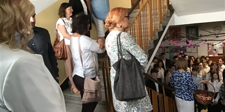 Powiększ grafikę: Nauczyciele stoją na schodach, niżej na korytarzu duża grupa uczniów