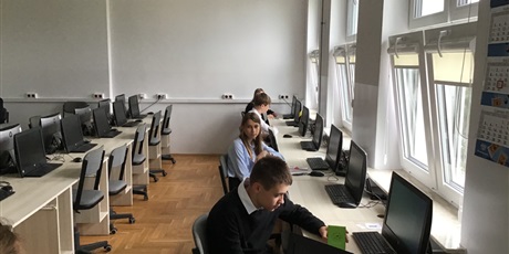 Powiększ grafikę: Czworo uczniów w sali lekcyjnej siedzą przed komputerami.